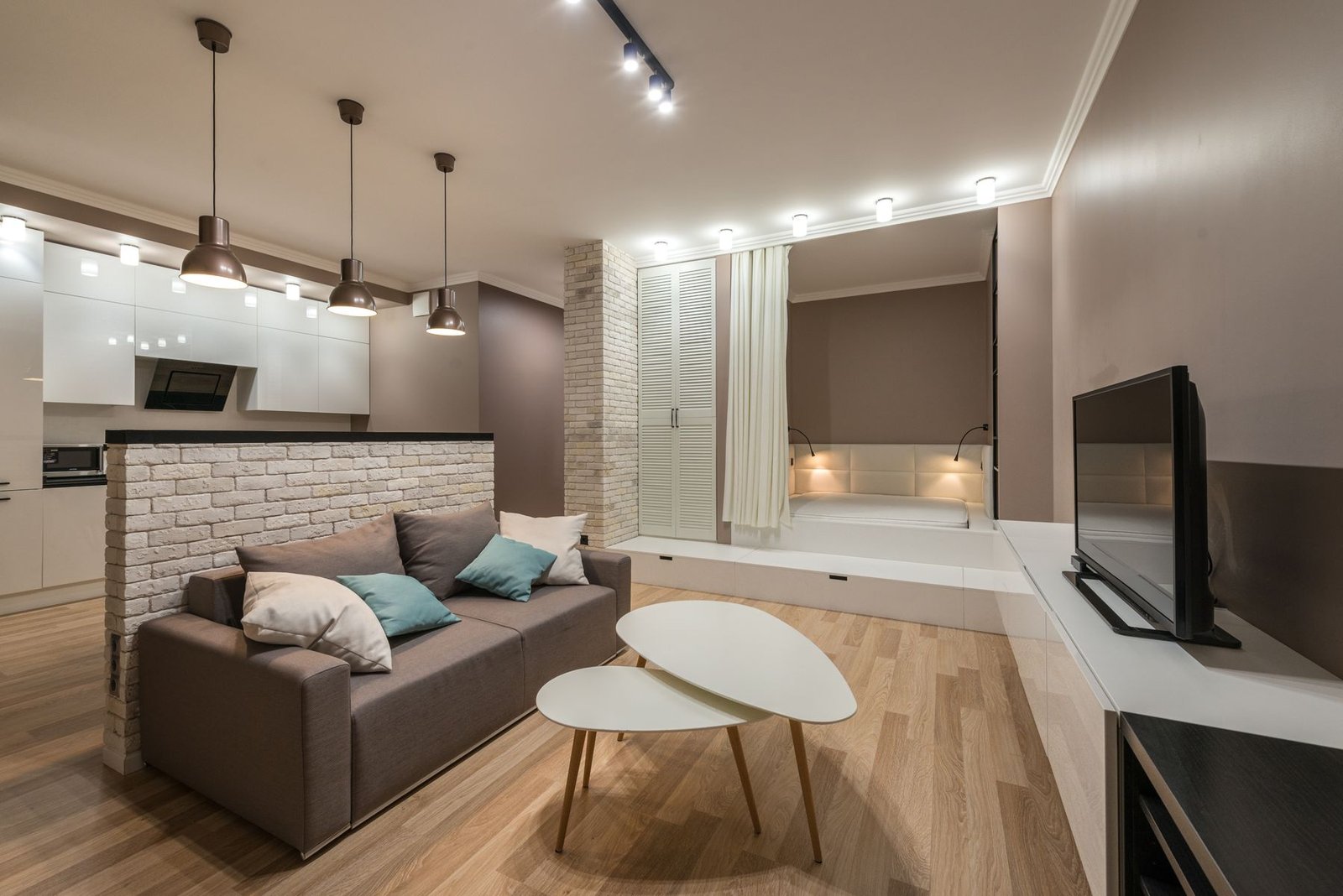 A compact living room with hanging lights, ceiling spotlights and small lights by the window seat.