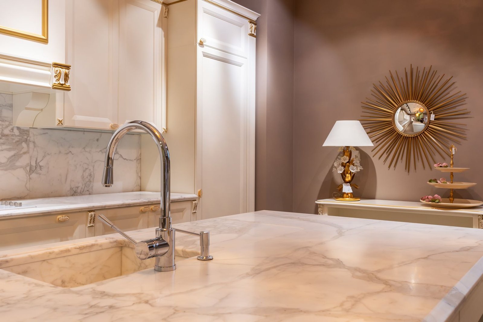 A polished, pale veined kitchen worktop with an inset sink, curved tap and visible front edge.